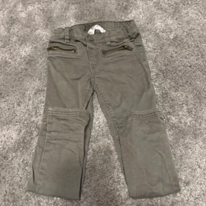 Olivfärgad byxan med dragkedjor - Snygga Oliv färgad byxan med dragkedjor vid fickorna och förstärkta knän. Perfekta för en cool och avslappnad stil. Byxan har en tight passform och är tillverkade i ett slitstarkt material.