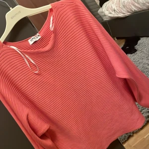 Rosa ribbad tröja från ONLY - Säljer en snygg rosa tröja från ONLY med ribbad struktur. Tröjan har långa ärmar och en avslappnad passform, perfekt för en stilren look. Passar bra till både jeans och kjol.