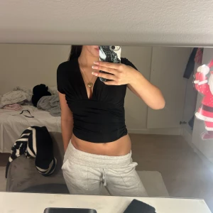 Svart fest topp från BikBok - Snygg svart topp från BikBok i storlek XS. Toppen har en djup v-ringning och korta ärmar, perfekt för en stilren look. Passar bra till både jeans och kjol. 🖤