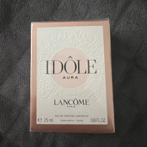 Idôle Aura Eau de Parfum från Lancôme - Säljer en elegant och lyxig parfym, Idôle Aura från Lancôme. Flaskan innehåller 25 ml av en fantastisk doft som är både fräsch och feminin. oöppnad och ny men kan rekommendera denna doft starkt! 
