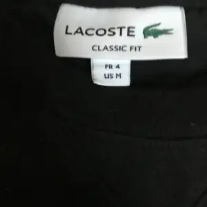 Säljer en klassisk svart tröja från Lacoste i storlek M. Tröjan har en enkel design med det ikoniska Lacoste-logotypen på bröstet. Den är långärmad och har en normal passform, perfekt för både vardag och avslappnade tillfällen.