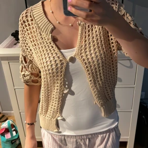 Kortärmad hålstickad kofta  - Säljer denna kofta som är hålstickad ifrån Zara. Storlek M men passar Xs/S, säljer den då den ej kommer till någon användning. Köpt för länge  sedan. Inga defekter. Så som ny. Vid frågor skriv gärna☺️🩷