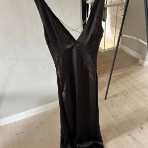 Svart balklänning  - Svart balklänning med slits och halft öppen rygg (kors med stenar se på bild) Använd 1 gång  Lite kort på mig (178cm)