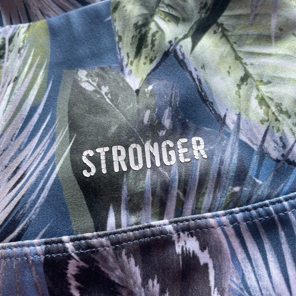 Storlek S, fint grönt mönster med blå bakgrund. Från Stronger. Sportswear.