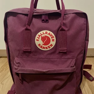 Kånken Ryggsäck - Royal Purple - Ryggsäcken är i gott skick och har använts endast i ett år. Den är slitstark, uthållig och väldigt rymlig - en perfekt ryggsäck för skolan/arbete eller utflykter. På sista bilden ser man lite slit, men det är endast en del av ryggsäckens charm. 💗