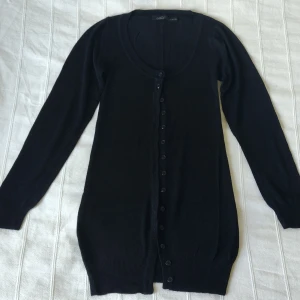 Svart kofta/tröja i 100% viskos  - Stilren svart finstickad kofta i en något längre modell. 100% viskos. En aning nopprig på något ställe. Storlek S 36/38, men passar även XS. 