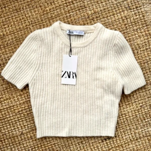 ZARA cropped short sleeve ribbeed knit sweater - New with tags- SHORT SLEEVE RIBBED KNIT SWEATER  Cropped sweater with round neck and short sleeves. Size S/36.    OUTER SHELL 54% polyester 34% acrylic 10% wool 2% elastane  Never used, with tags.