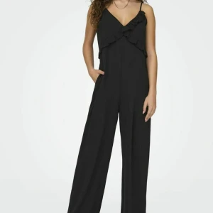 Svart jumpsuit från NLY Trend - Säljer en stilren svart jumpsuit från NLY Trend i storlek XS. Den har smala axelband och en snygg volangdetalj framtill. Perfekt för festliga tillfällen eller en utekväll. Materialet känns mjukt och bekvämt. Passa på att köpa denna eleganta jumpsuit!