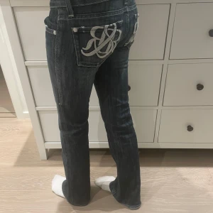 Mörkblå jeans med broderad bakficka - Säljer ett par snygga mörkblå jeans  från rock and republik med en cool broderad design på bakfickorna. De har en låg midja och en bootcut passform!