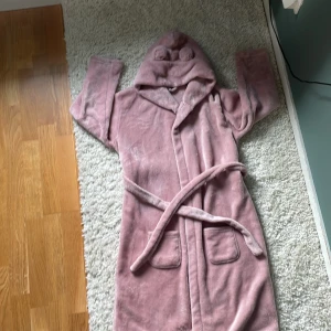 Rosa morgonrock med öron på luvan  - En rosa morgon rock som är storlek ca 146. Säljer den för 70kr + frakt. Kontakta för köp.