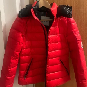 Moncler jacka - Moncler köpt vintage. Dragkedjan fungerar inte men det är något jag kan tänka mig kan fixas. Den har några lösa trådar och ett litet hål som jag skickar bild på privat. Jag kan inte garantera något äkthetsbevis utöver loggorna och lappen