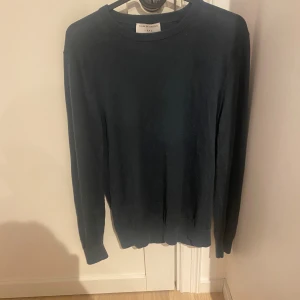 Mörkblå ulltröja från Filippa K - Säljer en stilren och bekväm mörkblå tröja från Filippa K. Den är gjord av 100% merino ull, vilket gör den perfekt för kyligare dagar. Tröjan har långa ärmar och en klassisk passform. Tveka inte att höra av er vid funderingar. 