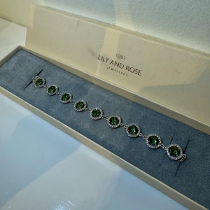 Lilly and Rosé - Miranda Crystal armband i silver och emerald grön - Oanvänd armband från Lilly and Rosé i form av klart kristallfoder som omger den huvudgröna smaragden/emerald. Satt i silver.