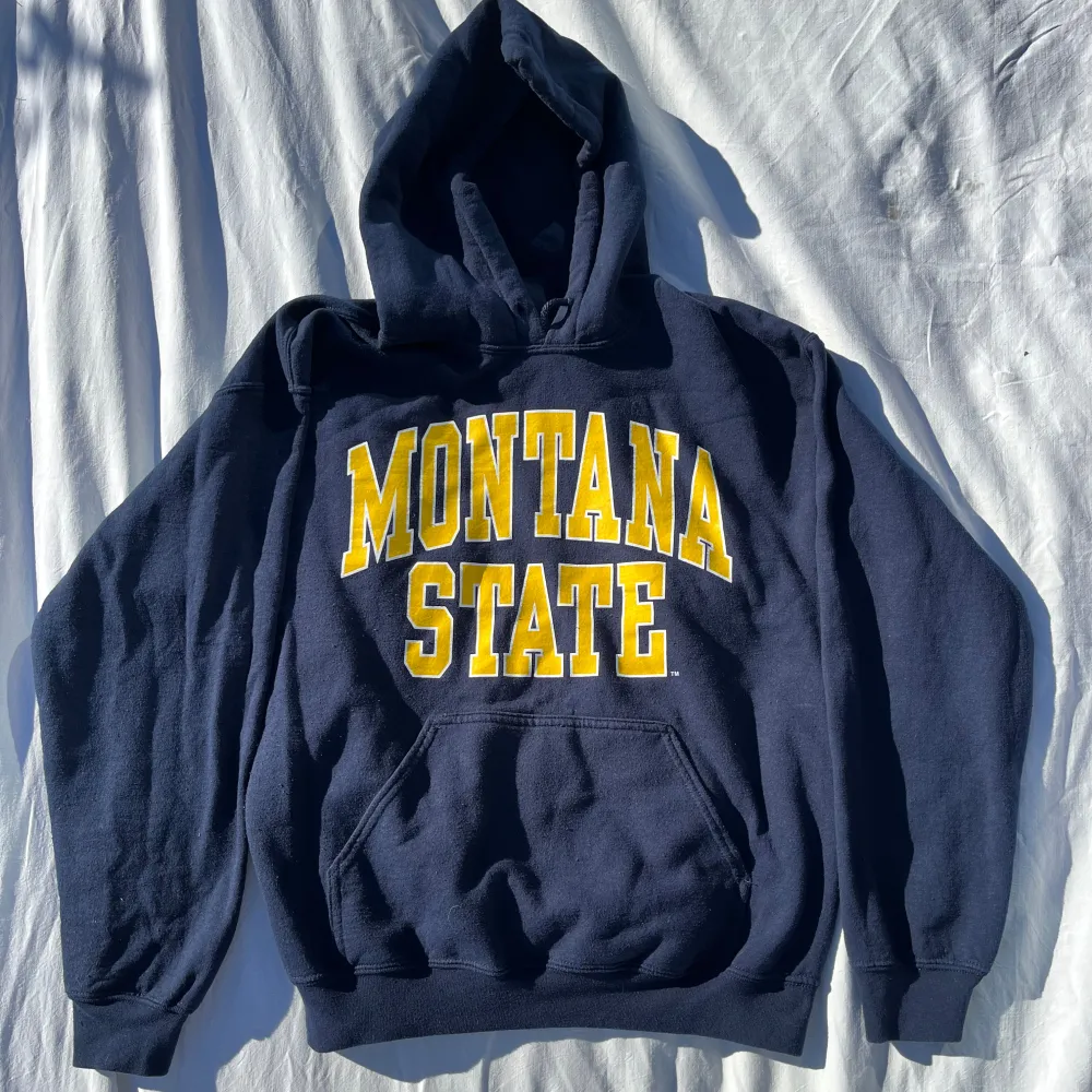 Mörkblå vintage hoodie från Gildan med stort gult 'Montana State'-tryck på framsidan. Den är i storlek M Unisex. Hoodies.