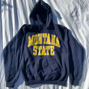 Mörkblå vintage hoodie - Mörkblå vintage hoodie från Gildan med stort gult 'Montana State'-tryck på framsidan. Den är i storlek M Unisex