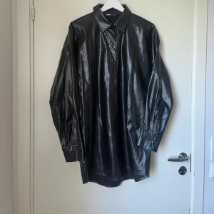 Svart jacka - Unik svart glasig/läder regnjacka, från Bikbok, i storlek s. Inga skador. Ser helt ny ut.