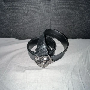 Versace bälte  - Säljer ett snyggt svart Versace meduza bälte i silver. Skärpet är i skinn och passar både till vardags och fest. 100% äkta ärvt.