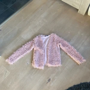 Pälsjacka - Säljer en supermysig rosa fluffig jacka från Gina Tricot i storlek XXS/xs. Perfekt för att hålla sig varm och stilren under kyliga dagar. Jackan har långa ärmar och är gjord i ett mjukt material . Passar perfekt till hösten