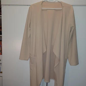 Rosa/beige kavaj/kofta - En "lättare" kavaj, lite likt en kofta. Passar utmärkt som "jacka" på våren men passar också att ha inomhus under hösten/vintern. Använd bara ett fåtal gånger men absolut inget som syns. Den passar M och i vissa fall L