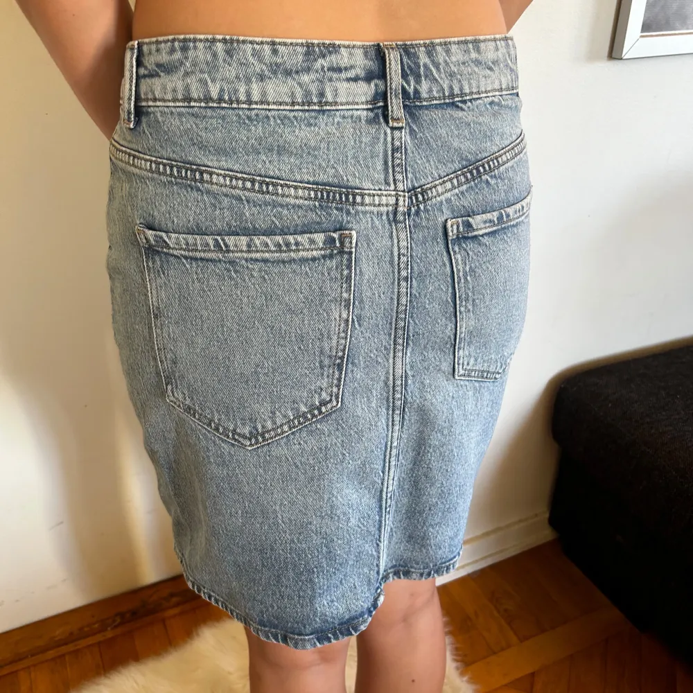 Säljer en superfin jeanskjol i ljusblå denim. Kjolen har en klassisk femficksdesign och stängs med en knapp och dragkedja framtill. Den är i en normal passform och slutar strax ovanför knäna, vilket gör den perfekt Materialet är slitstarkt och ger en snygg vintage-look.. Kjolar.