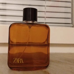Brun parfymflaska från Zara - Säljer en stilren brun parfymflaska från Zara. Flaskan har en fyrkantig form med rundade hörn och ett svart lock. Perfekt för den som gillar en enkel och elegant design. Passar både till vardags och fest!