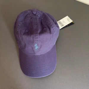 Polo Ralph Lauren Keps Lila - Polo Ralph Lauren Keps lila  One size (justerbar) Oanvänd helt ny Nypris: 600  Hör av dig vid fler frågor!