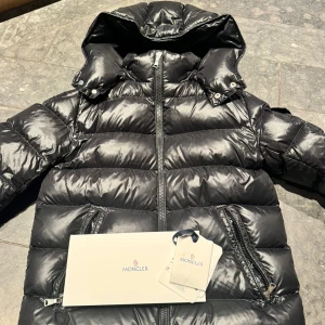 Svart pufferjacka från Moncler - Säljer en snygg och varm svart Maya jacka från Moncler. Den har en dragkedja framtill och praktiska fickor med dragkedja . Köpt i oktober förra året men sparsamt använd verkligen! st 14 år
