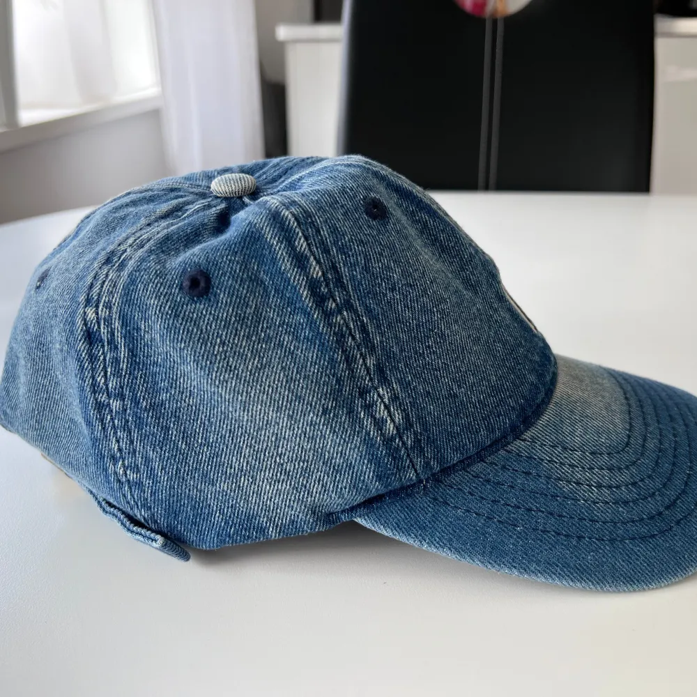 Blå keps i jeansmaterial med vitt tryck på framsidan. Säljs pga att den tyvärr inte kom till användning 💙 Vet ej var den kommer ifrån.  (ALDRIG ANVÄND). Asusteet.