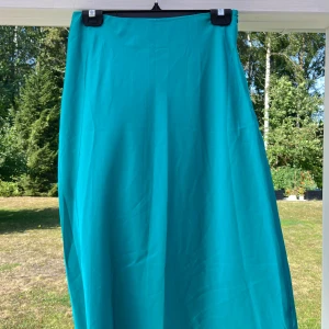 Grön midikjol i satin - En grön midikjol i satin med stängning vid vänster höft i form av en dragkedja. Tunt och fint material, passar till utekvällen eller utlandsresan 💚 Passar bra till mig som har S-M i nederdelar.  (ALDRIG ANVÄND)  Längd: 77 cm Midja: 74 cm Höft: 101 cm