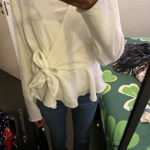 Vit Blus från nelly  - Vit omlottblus från nelly🤍. Inga defekter alls och är som helt ny. Lite genomskinlig  men funkar med en vit bh eller en tröja under. Storlek 36. Köpt för 300 kr men säljer för 150. Pris går alltid att diskutera💕