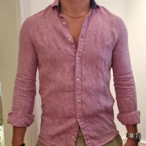 Rosa linneskjorta - Rosa långärmad skjorta av 100% linne. Krage med slag och ärmslut med knappar. Använd ett fåtal gånger, mycket bra skick. Slim fit. 