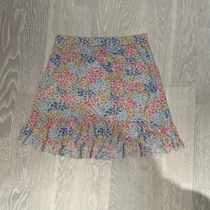 Blommig kjol från Gina Tricot - Säljer en superfin blommig kjol från Gina Tricot i storlek L. Den är ganska tajt så skulle nog säga mer som en M. Kjolen har ett färgglatt mönster med blommor i somriga fina färger. Den har en söt volangdetalj längst ner som ger en extra touch. Perfekt för vår och sommar😍💐 Skriv för mer bilder eller mått!