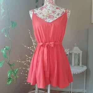 NY romper, kjolsvida ben & knytband i midjan - Ny i påse. Korall. Petite, passar kortare torso. Ena hällan har halvt lossnat, bara att nästa fast om man vill. ~ STOR rensning, klänningsbonanza & erbjudanden i min shop ~