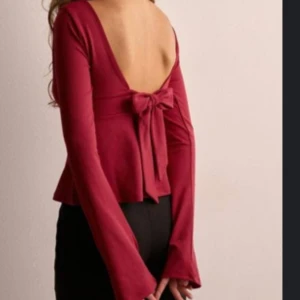 Röd topp med öppen rygg från Nelly - Snygg röd topp från Nelly med öppen rygg och knytband. Toppen har långa ärmar och en djup v-ringning framtill. Perfekt nu till julen😍Oanvänd och lappen är kvar. Storlek S