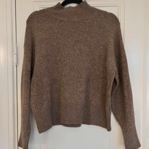 Beige stickad polotröja - Mysig beige stickad polotröja i mycket bra skick. Perfekt för kyliga höst- och vinterdagar. Tröjan har långa ärmar och ribbade detaljer vid hals, ärmslut och nederkant. Superfin att matcha med jeans eller kjol för en avslappnad look.