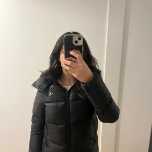 Svart dunjacka från Calvin Klein Jeans - Säljer en snygg svart dunjacka från Calvin Klein Jeans i storlek XS. Använd en gång i princip helt ny 