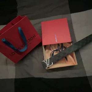 Rutig Louis Vuitton bälte - Säljer ett snyggt Louis Vuitton bälte i rutig design. Bältet har en stilren silverfärgad LV-spänne och är perfekt för att ge din outfit en lyxig touch. Passar både till vardags och fest. Kommer med originalförpackning.