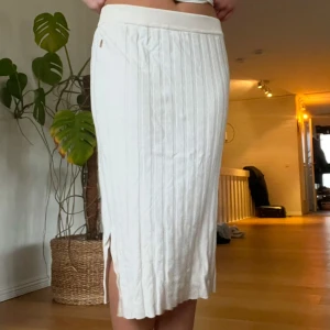 Vit ribbad kjol - Vit kjol med slits på sidan säljs i storlek M från Pernilla Wahlgrens kollektion🤍 Kjolen slutar ungefär 15cm under knäna!