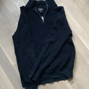 Svart tröja med dragkedja från H&M - Snygg svart tröja från H&M i slim fit med dragkedja vid halsen. Perfekt för en stilren look. Tröjan har långa ärmar och är tillverkad i ett mjukt material.