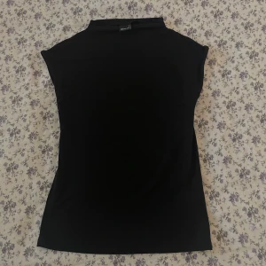 Svart tight topp - Snygg svart tight topp med korta ärmar och hög hals. Perfekt för en stilren look. Passar bra till både jeans och kjol.