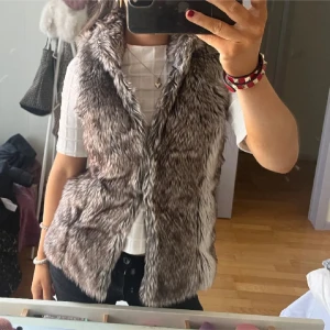 Pälsväst från ONLY - Snygg och trendig pälsväst från ONLY i en naturlig brun och grå färg. Västen har en mjuk och fluffig textur som ger en lyxig känsla. Perfekt för att hålla sig varm och stilren under kyligare dagar. Storlek s och aldrig använt💕💕