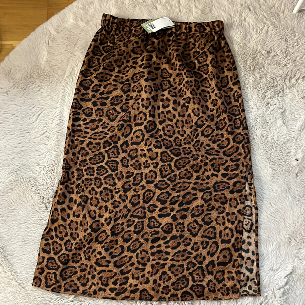 Säljer en supercool leopardmönstrad kjol i brunt och svart. Kjolen är i ett mjukt och glansigt material, perfekt för att sticka ut på festen eller bara för en vardagslook med attityd. Den har en elastisk midja för extra komfort. Passar perfekt till både sneakers och klackar! Men slits på båda sidorna.. Hameet.