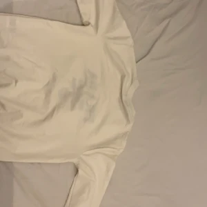 Vit långärmad tröja från Prada - Snygg vit långärmad tröja från Prada med svart text och logga på framsidan. Perfekt för en stilren look.