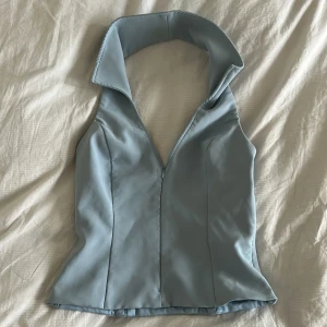 Ljusblå ärmlös topp med öppen rygg - Snygg ljusblå ärmlös topp med en öppen rygg och dragkedja framtill. Använd endast 1 gång. Från Zara storlek 38/M