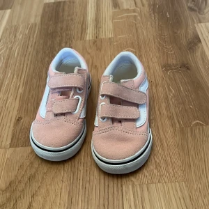 Rosa sneakers från Vans - Söta rosa sneakers från Vans med vita detaljer och kardborreband för enkel på- och avtagning. Skorna har en klassisk vit sula med brunt mönster undertill. Storlek 20 (11 cm) 