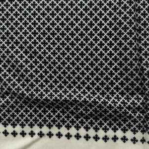 Svartvit halsduk med geometriskt mönster - Elegant svartvit halsduk med ett stilrent geometriskt mönster. Perfekt för att ge en klassisk touch till din outfit. Den har fransar i kanterna som ger en extra detalj.