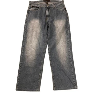 Baggy jeans med broderad detalj - Snygga blå baggy jeans med en cool broderad detalj på bakfickan. Bra skick men Lite heelbite 