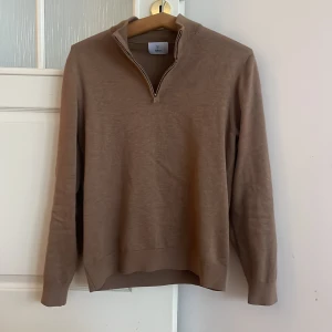 Brun half zip från Bläck - Säljer en stilren brun half zip från Bläck med dragkedja vid halsen. Tröjan har långa ärmar och en ribbad krage. Perfekt för en avslappnad men snygg look. Priset kan diskuteras vid snabb affär.