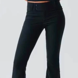 Svarta kostymbyxor - Snygga svarta kostymbyxor i lågmidjad modell med två knappar fram. Jätte fina men tyvär lite långa för mig då jag är 155 så inte använda!