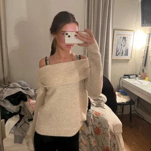 Beige offshoulder tröja - Säljer en stilren beige offshoulder tröja med ribbade detaljer. Perfekt för en avslappnad och trendig look. Passar bra till både jeans och kjol.